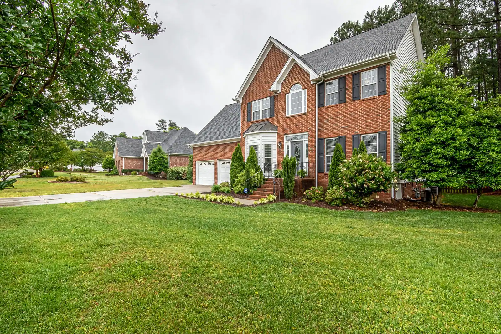 Deep green mowed lawn in front of a two-story brick home